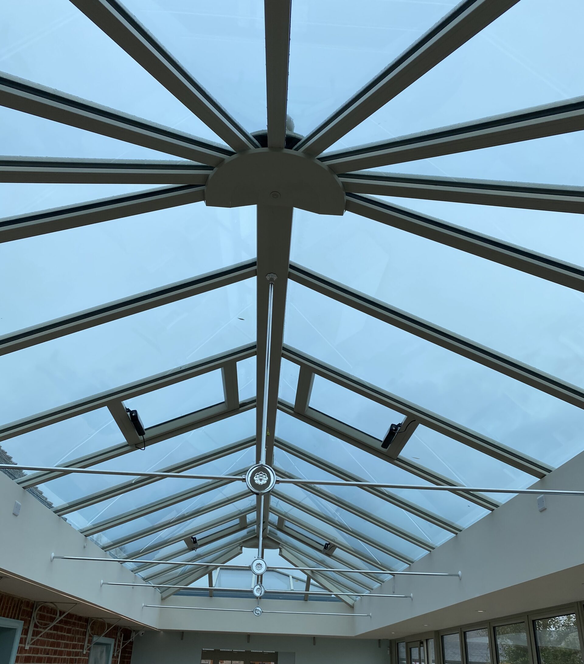 Interior glass roof structure with metal beams and blue-tinted panels forming pitched skylight in conservatory; part of Glaze Ltd project.
